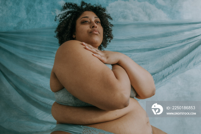 close up portrait of a plus size afro indigenous person looking up with arms crossed