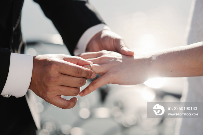 Closeup photo of bride and groom holding golden wedding rings on hands