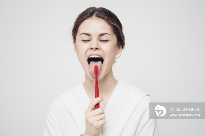 pretty woman in white robe brushing tongue hygiene