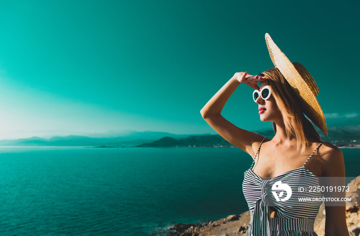 Young redhead girl in hat and dress with sea coastline on Balos, Crete, Greece