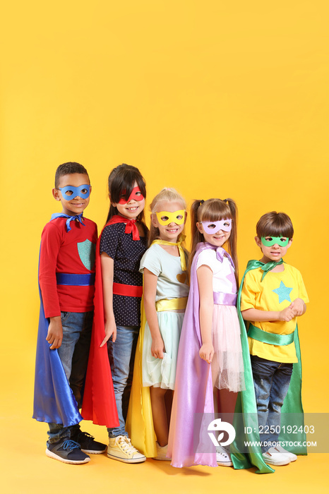 Cute little children dressed as superheroes on color background