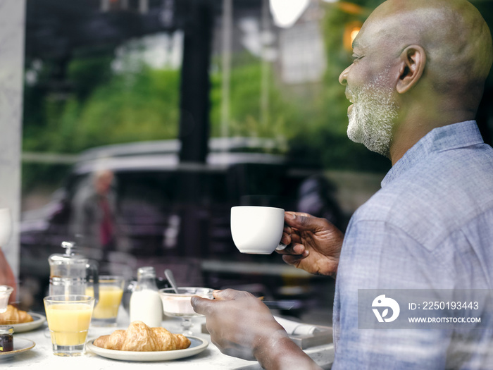 UK,ÊMan at hotel breakfast table seen through window