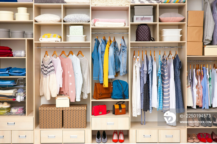 Large wardrobe with female clothes and accessories in dressing room