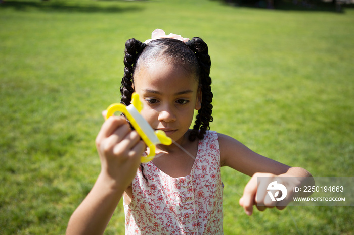 Girl (6-7) with plaits holding yellow kite handle green lawn in background