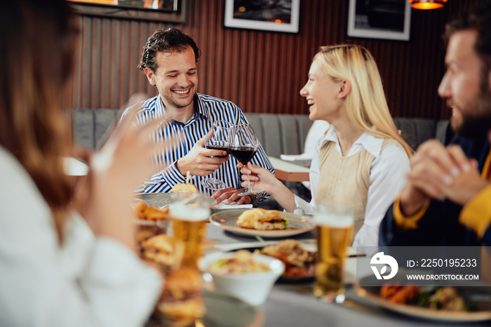 Friends dressed smart casual making a toast while sitting at restaurant.