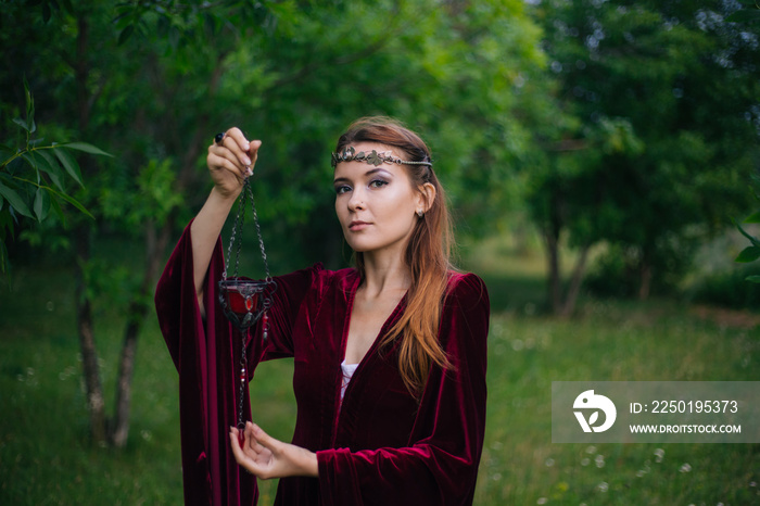 a girl in a red medieval dress holds a lamp in her hands. Fantasy. Woman elf