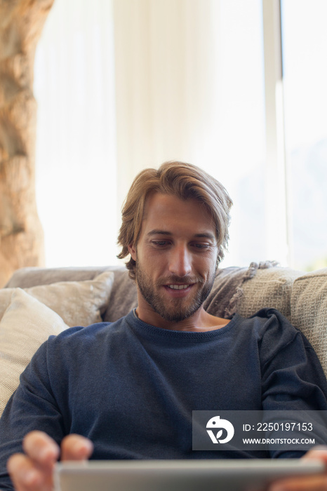 Young man using digital tablet on sofa