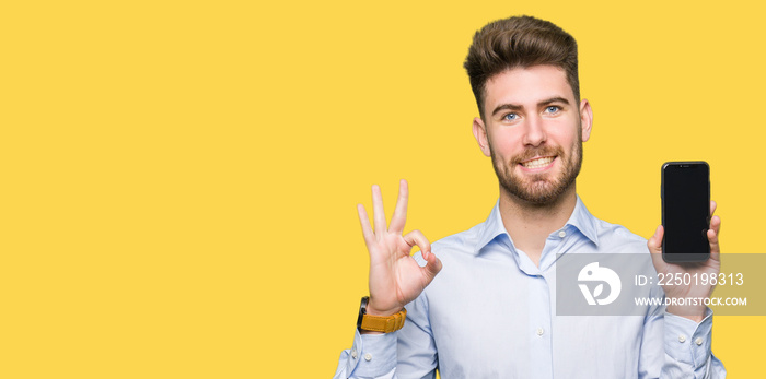 Young handsome man business showing smartphone screen doing ok sign with fingers, excellent symbol