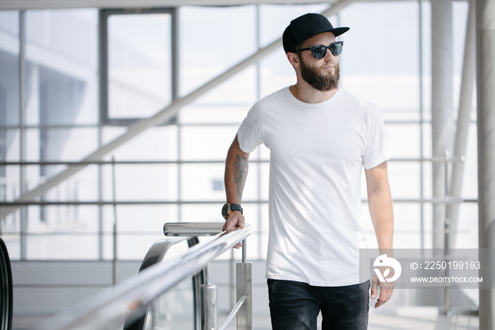 Hipster handsome male model with beard wearing white blank t-shirt and a baseball cap with space for