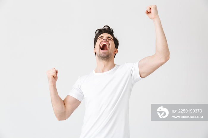 Excited happy young man posing isolated over white wall background.