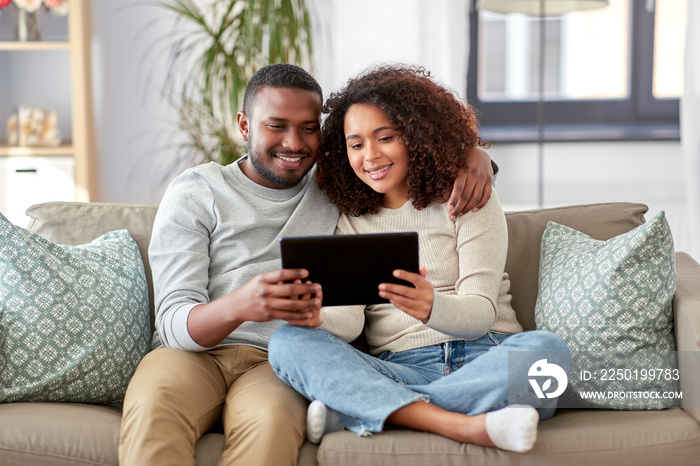 technology, internet and people concept - happy african american couple with tablet computer at home