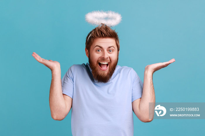 Portrait of bearded angelic man with holy nimbus looking at camera with toothy smile, expressing pos