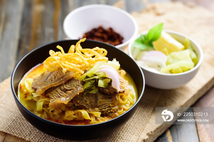 Northern Thai food (Khao Soi), Spicy curry noodles soup with beef in a bowl eating with crispy deep-