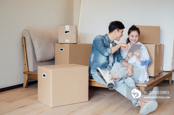 Young Asian couple using tablet computers in new home