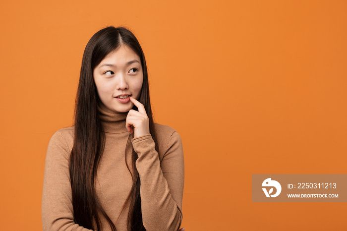 Young pretty chinese woman relaxed thinking about something looking at a copy space.