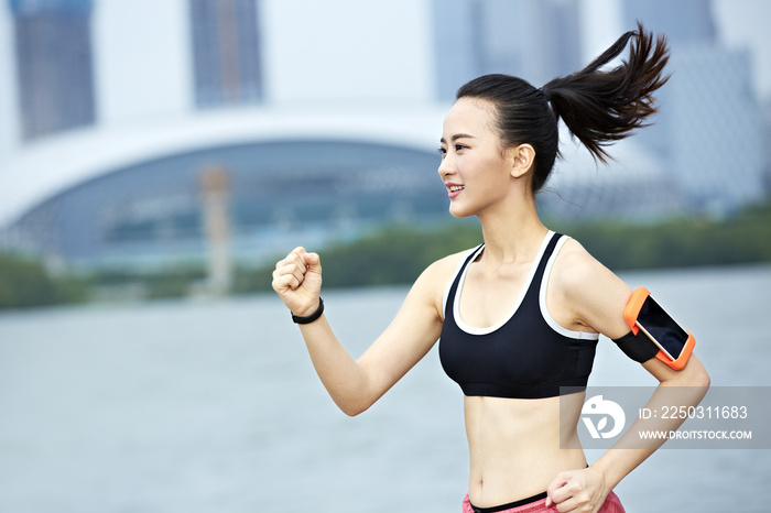 young asian woman running by a lake