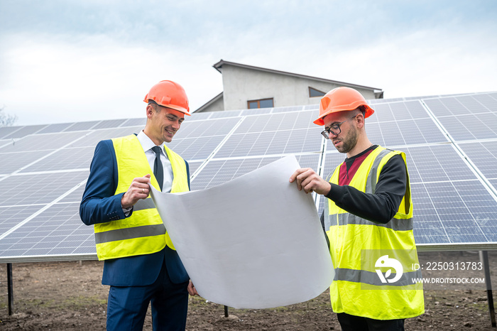 两位工作服专业人士讨论太阳能电池板及其影响。