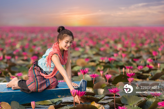 美丽的女人坐在荷花园的船上。