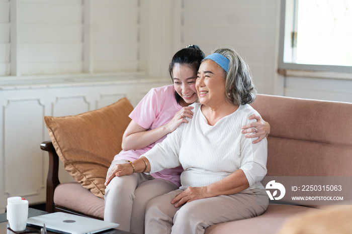 Cute Asian adult daughter embracing her mother with love in living room at home