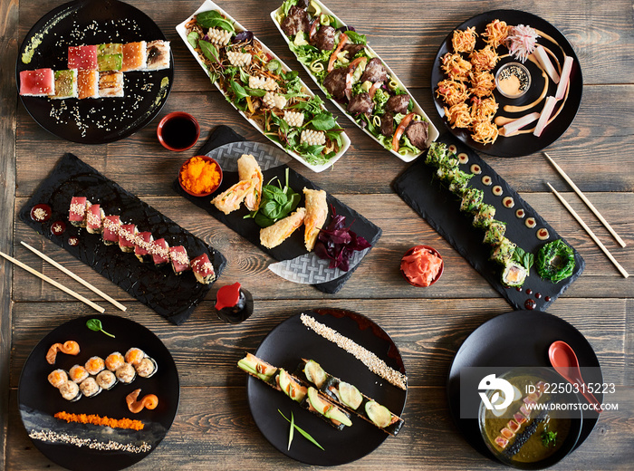 Serving tasty sushi rolls and other traditional japanese food on wooden table in restaurant