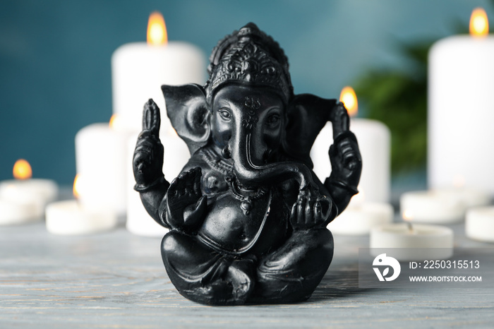 白色木桌上的印度教神Ganesha。背景是蜡烛