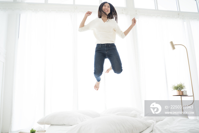 Asian woman jumping on the bed. happy concept