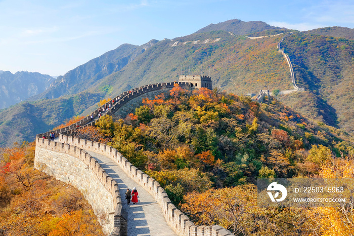 Two unrecognizable tourists walk along the walkway atop the Great Wall of China.