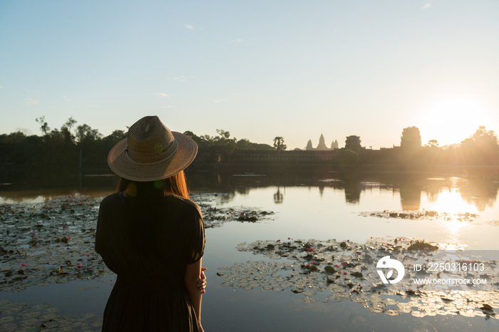 The silhouette of unidentified a female tourist looking at Angkor Wat from the outer wall, Siem Reap