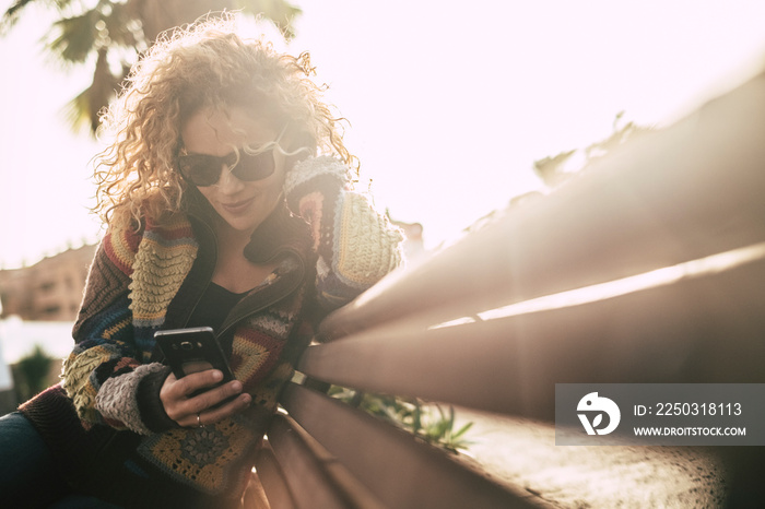 Autumn season colors with beautiful adult attractive blonde curly woman use mobile phone sitting on 