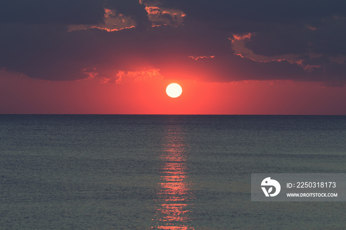 Sunset / sunrise over ocean / sea horizon with clouds.