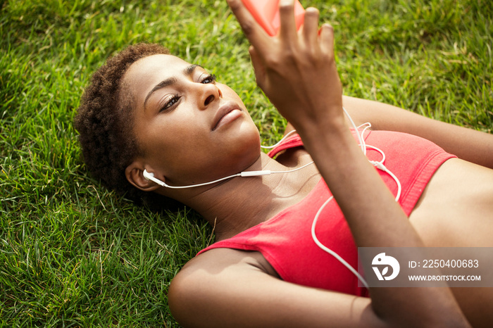 Woman wearing earphones listening to music on smartphone outdoors