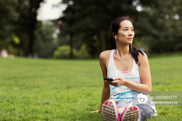 Young woman listening to music on smartphone in park