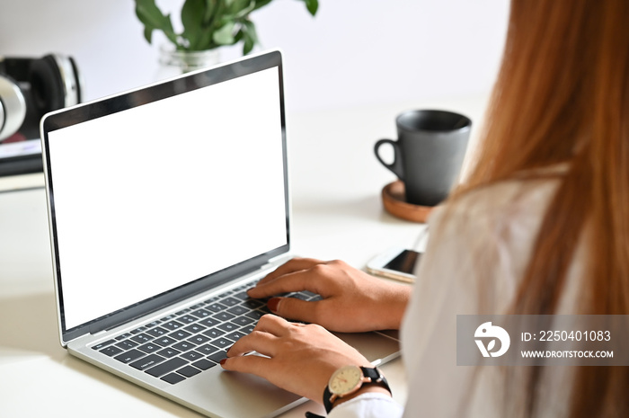 Young woman using mockup laptop computer on table.