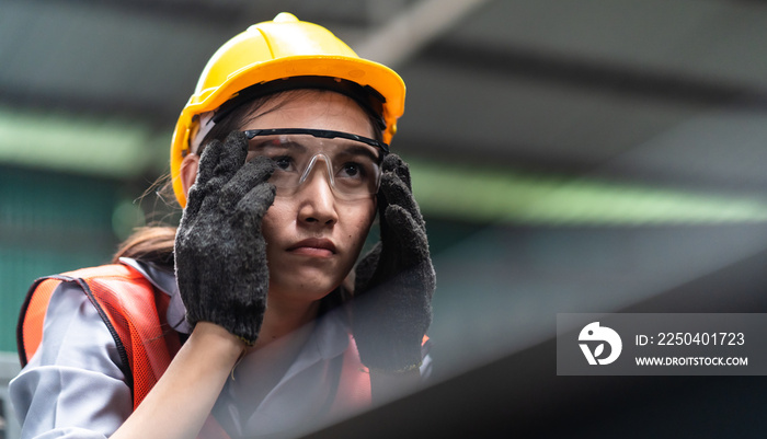 Woman worker wearing safety goggles control lathe machine to drill components. Metal lathe industria