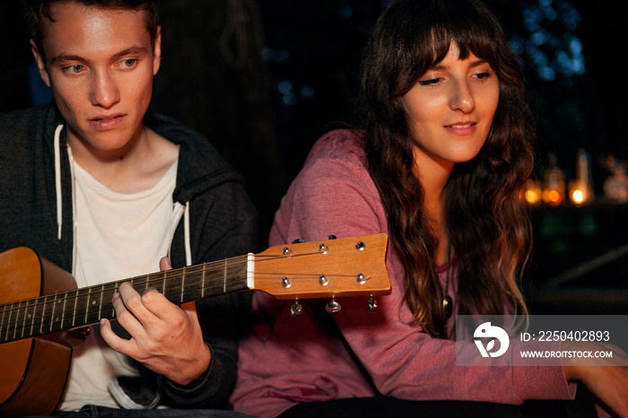 Young man playing guitar on camping trip