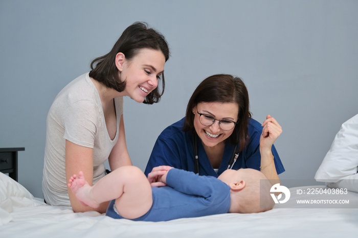 Pediatrician in blue uniform with stethoscope talking to young mother of baby