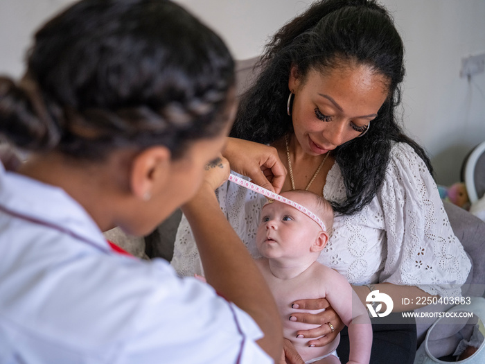 Nurse taking growth measurements of baby girl (2-5�months)