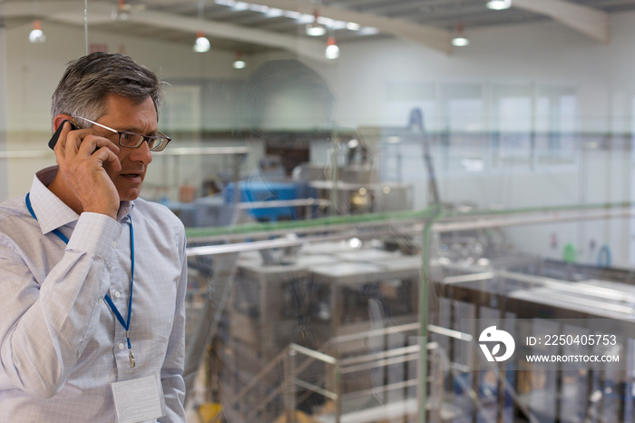 Male manager talking on smart phone above factory floor