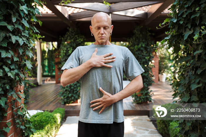 Motivated young fitness man doing breathing exercises