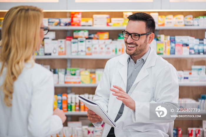 Cheerful pharmacist talking to his female colleague.