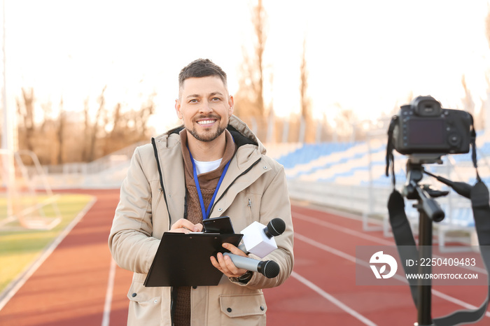 Male reporter with microphones at the stadium