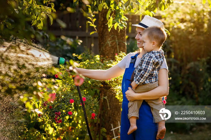 woman gardener with son watering garden