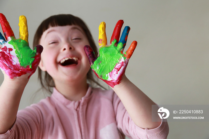 Cute little girl with painted hands. Isolated on gray background.