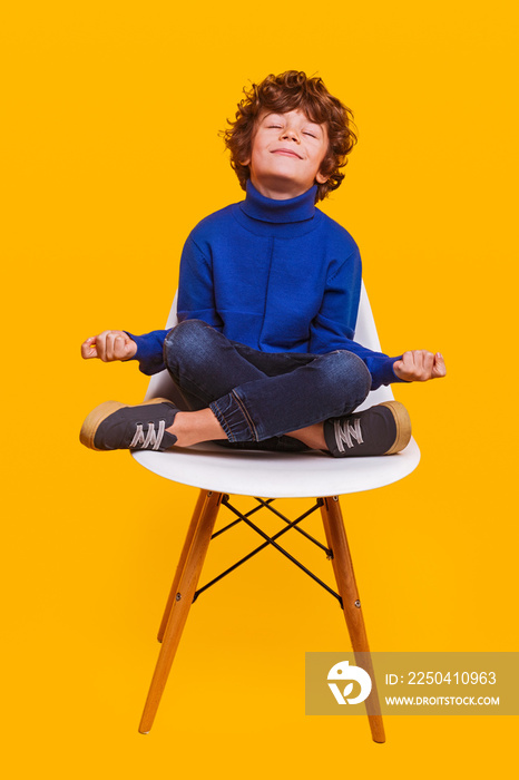 Happy boy meditating on chair