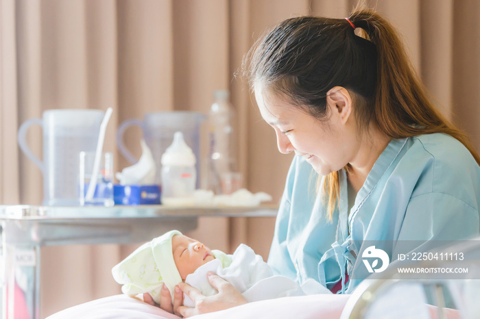 Selective focus of Happy asian mother looking newborn baby boy sleeping in hand at hospital