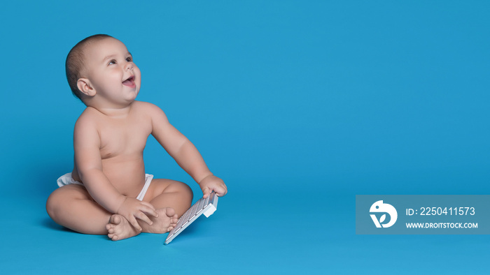 Baby with keyboard of modern computer looking up