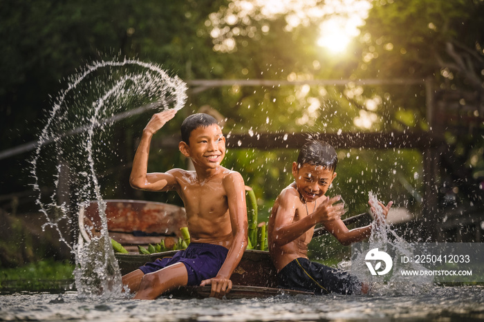 Two boys splashing in water near the Damnoen Saduak Floating Market