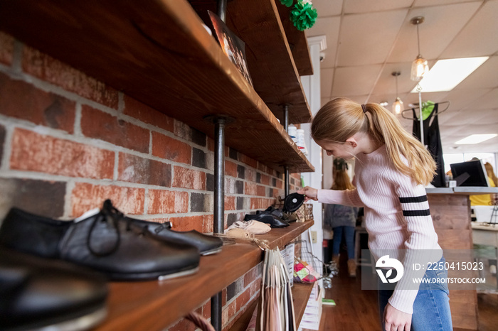 Side view of girl with blond hair looking shoes in store