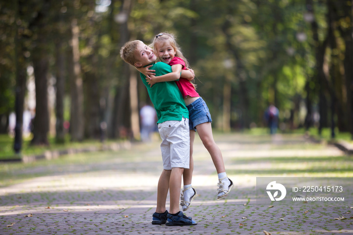 Two cute young funny smiling children, girl and boy, brother holding sister in his arms, having fun 