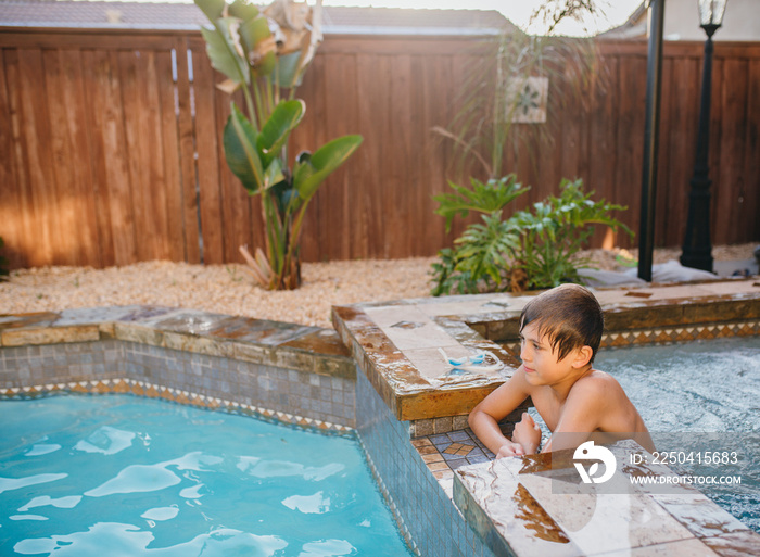 Side view of thoughtful boy looking away while relaxing in swimming pool